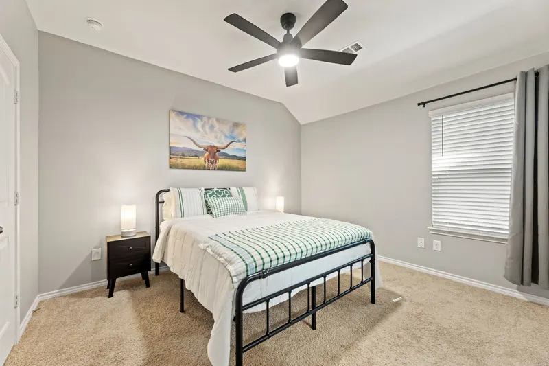 Primary bedroom with queen bed, longhorn artwork and ceiling fan